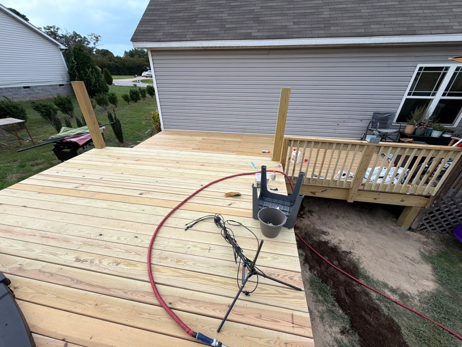 Completed pressure-treated deck with railing connecting the house to the pool